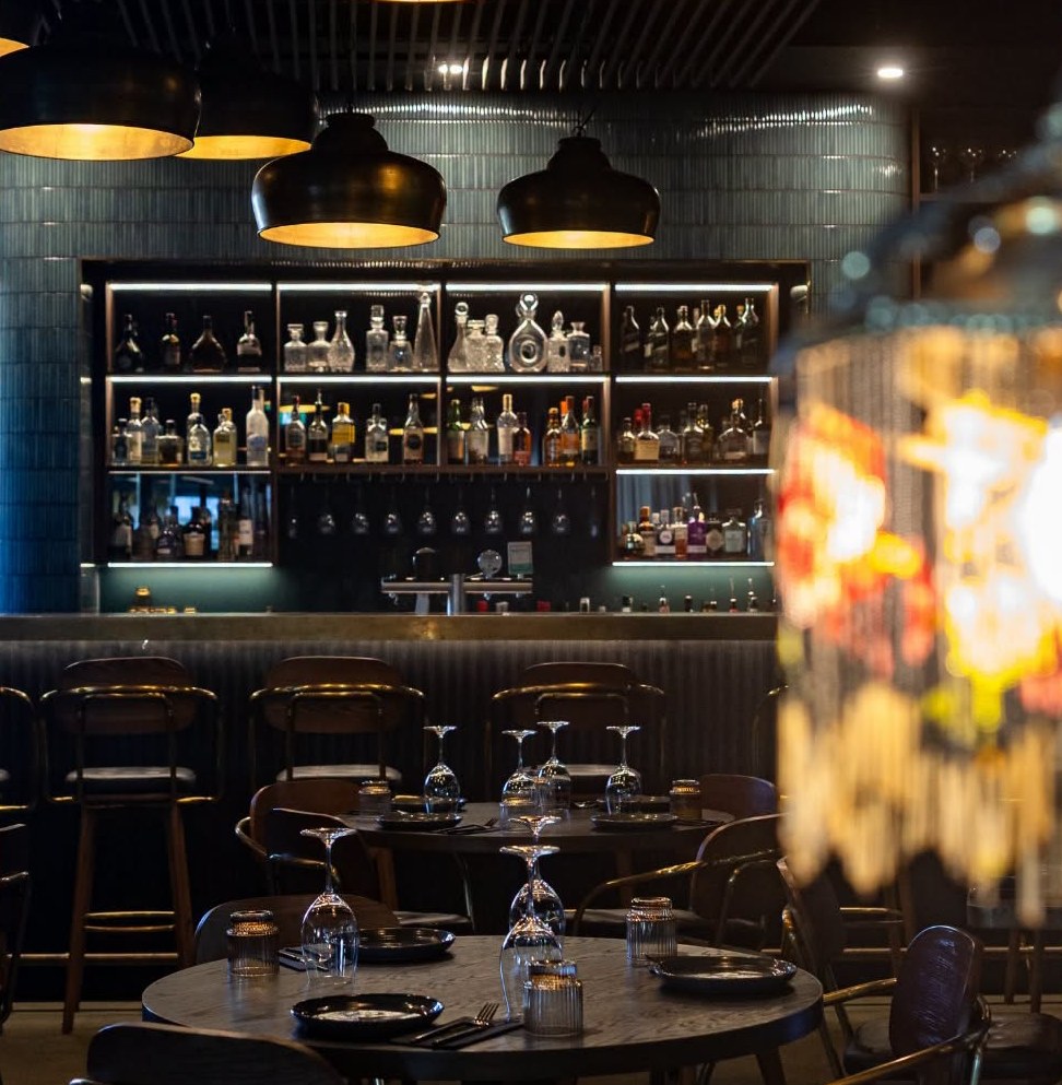 Round tables in front of the lit back bar