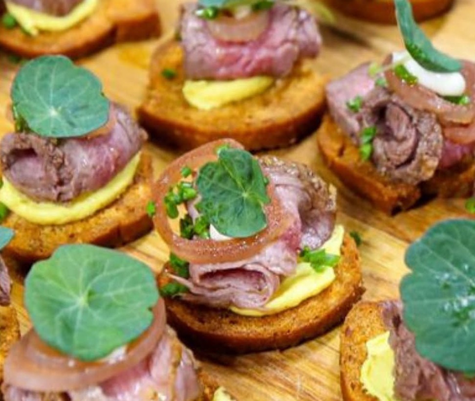 Roast beef canapés on toasts, topped with nasturtium leaves