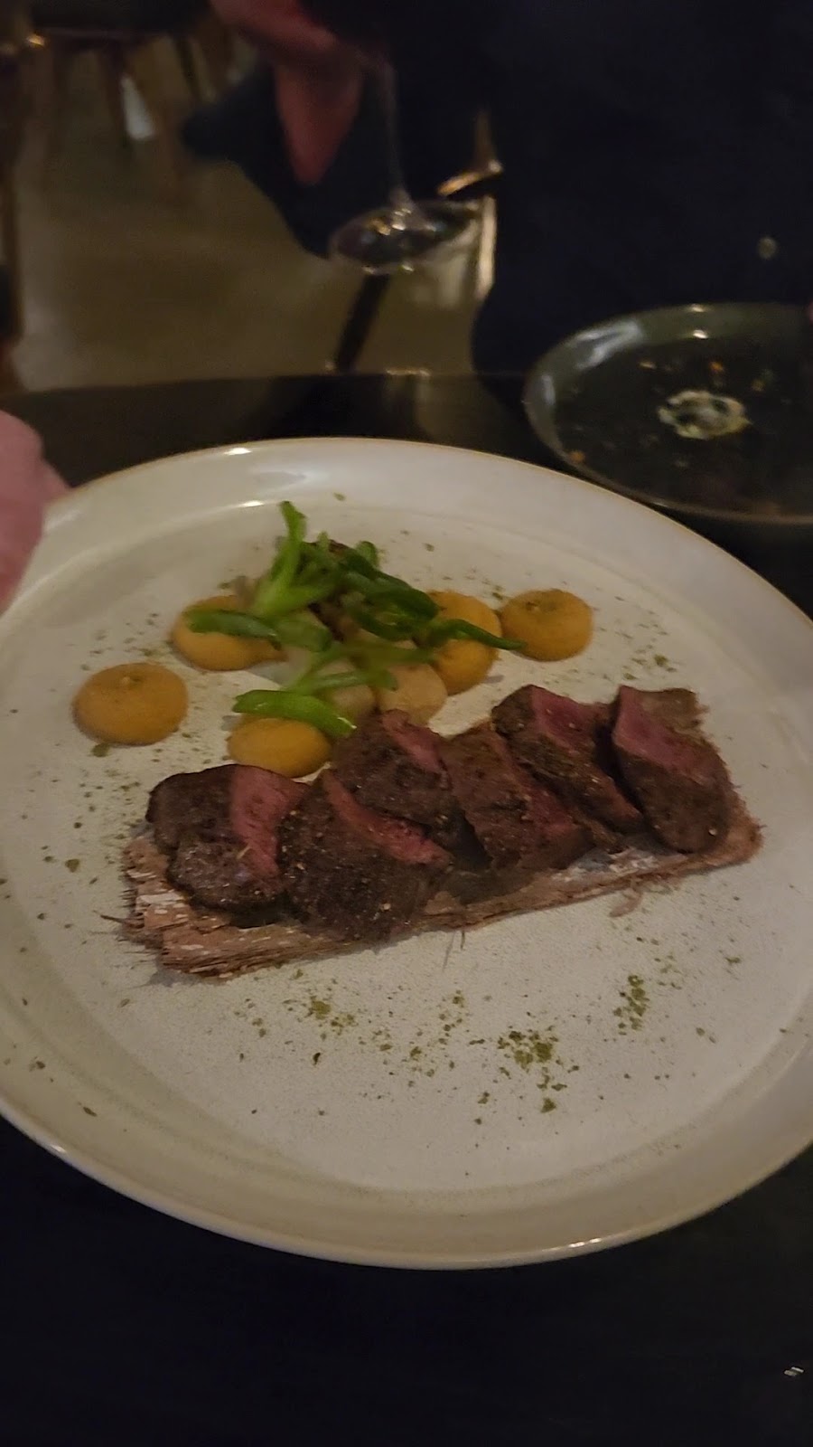 A plated steak with purée and greens