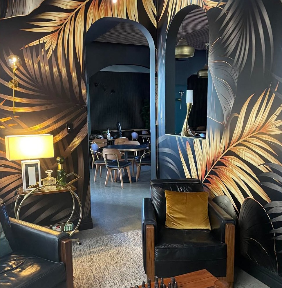 The lounge nook with palm leaf wallpaper and leather armchairs